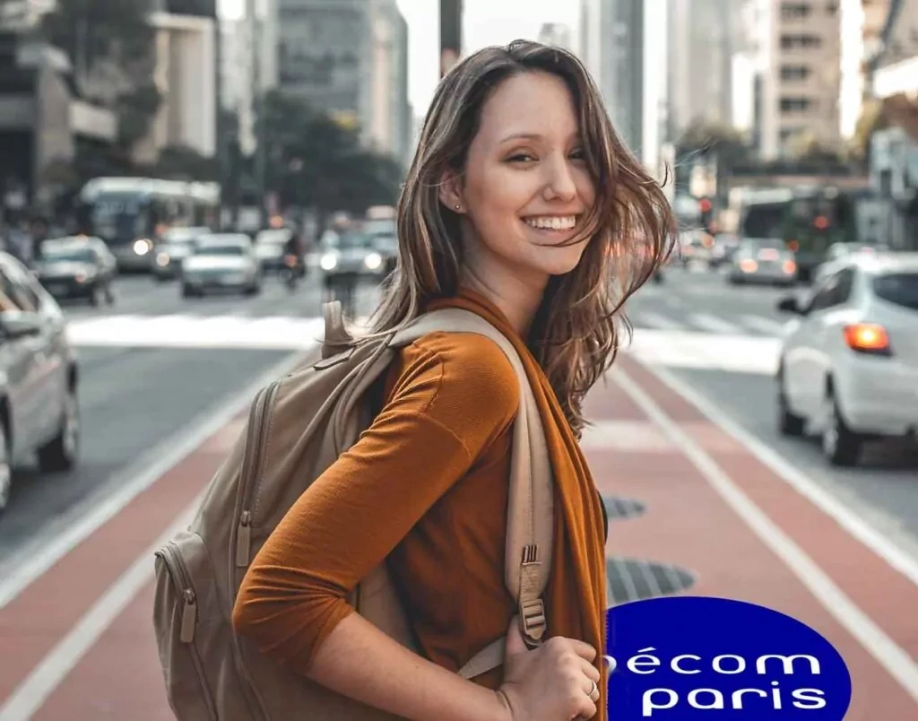 Jeune étudiante souriante avec un sac à dos marchant dans une grande avenue, symbole des études supérieures à Ipécom Paris