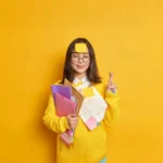 Jeune élève concentrée et confiante, tenant des dossiers scolaires, symbolisant la préparation des épreuves finales nationales du baccalauréat hors contrat