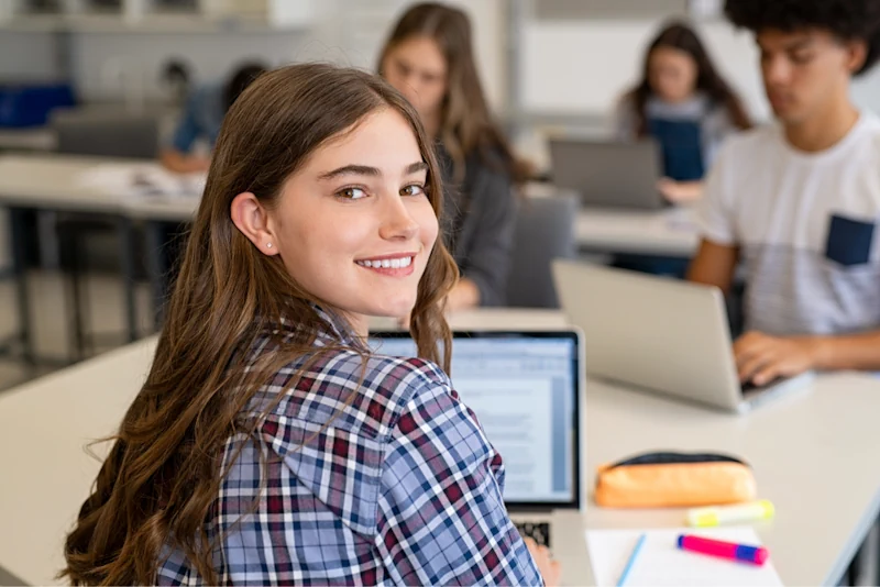 Lycéenne souriante travaillant sur ordinateur dans une classe du lycée Ipécom Paris