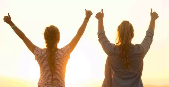 Deux lycéennes levant les bras en signe de réussite au coucher du soleil, symbolisant la confiance et les progrès obtenus grâce aux stages de préparation au bac Ipécom Paris.