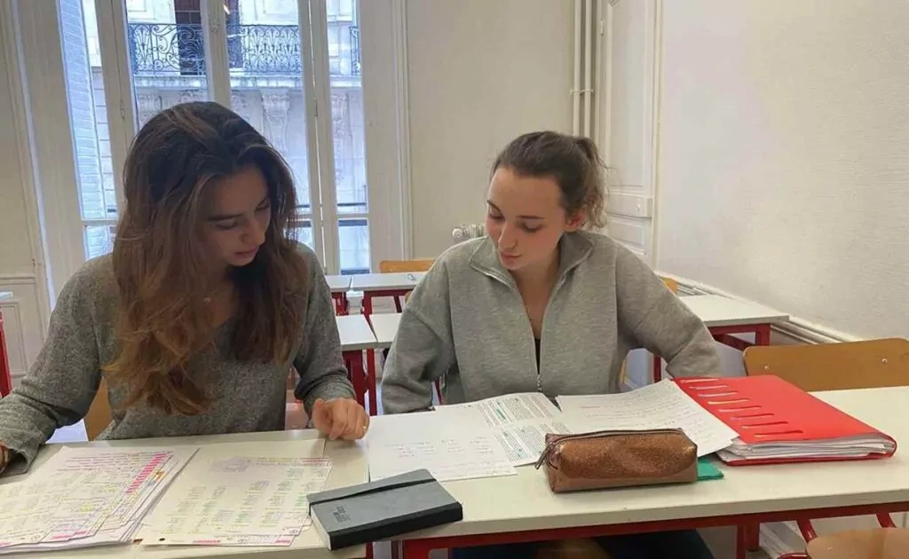 Deux étudiantes travaillent ensemble sur des exercices pendant un stage de maths prépa ECG à Ipécom Paris.